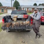 man posing with caught beavers and musk rats in pick up truck