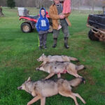 Man posing with his children and three dead coyotes